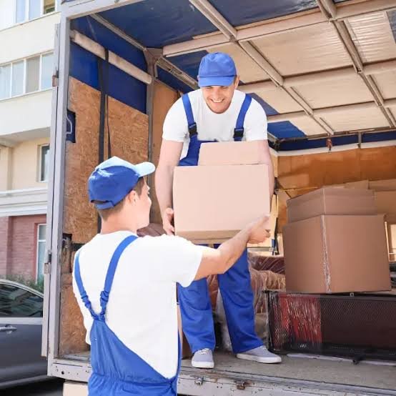 Caminhão de frete carregado com móveis e volumes sendo amarrados